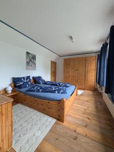 a bedroom with a bed with blue sheets and wooden floors at Landhaus Oldorf in Rodenäs