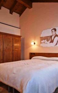ein Schlafzimmer mit einem weißen Bett mit einem Bild an der Wand in der Unterkunft Meublè Lo Miete Viei in Champoluc
