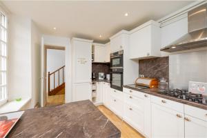 a kitchen with white cabinets and a counter top at Splendide maison de maître à 50m du port et 100m de la plage in Barfleur +6 photos
