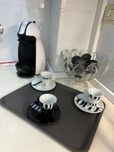 Una bandeja negra con tazas y platillos sobre un mostrador. en Vivi Aguilera apartament, en Bolonia