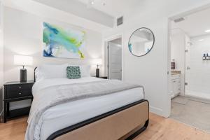 a white bedroom with a bed and a mirror at Downtown Luxury 1BD- Poo Spa Bowl Golf Gym Parkng in McIntyre Building Condominium