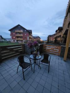 a patio with three chairs and a table with flowers at Apartmán Andrea Tatragolf in Veľká Lomnica