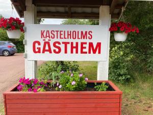 a sign in a red flower box with flowers at Kastelholms Gästhem in Sund