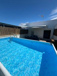 une grande piscine à l'eau bleue dans une maison dans l'établissement Casa María Oliva 50m playa, à El Palmar