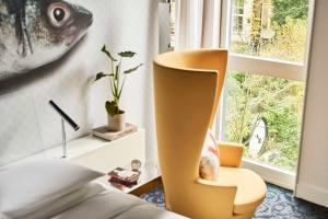 a living room with a chair and a window at Andaz Amsterdam, Prinsengracht, By Hyatt in Amsterdam