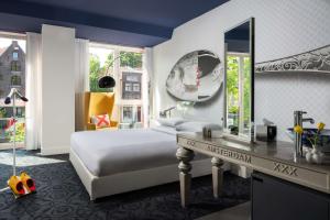 a bedroom with a bed and a desk with a mirror at Andaz Amsterdam, Prinsengracht, By Hyatt in Amsterdam