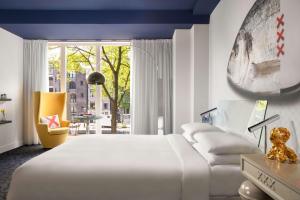 een slaapkamer met een wit bed en een gele stoel bij Andaz Amsterdam, Prinsengracht, By Hyatt in Amsterdam