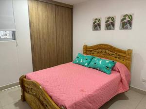 een slaapkamer met een bed met roze lakens en een blauw kussen bij Apto completo Bello horizonte in Playa Bello Horizonte +6 foto's