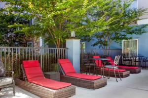 a patio with red chairs and a table and trees at Comfort Suites Nashville Airport - BNA in Nashville