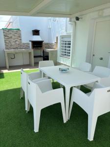 une table blanche et des chaises blanches sur une terrasse dans l'établissement Casa María Oliva 50m playa, à El Palmar
