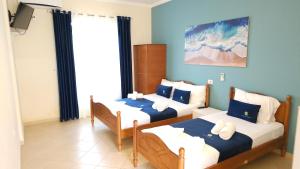two beds in a room with blue walls at Friends House - Borsh Hotel in Borsh