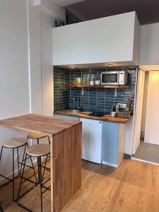una cucina con bancone, sgabelli e forno a microonde di Grand studio mezzanine cathédrale de Lisieux a Lisieux