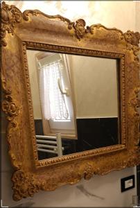 Un espejo dorado adornado en una pared con una ventana. en Patty house, en LʼAquila