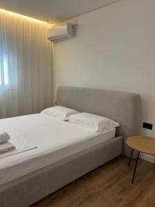 a bed with white sheets and a table in a room at Sophie Apartment in Tirana