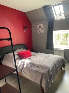 una camera da letto con un letto con una parete rossa di La maison des caves a Châteauvieux Altre 11 foto