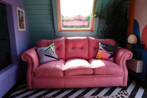 a pink couch in a room with pillows on it at Ammonite Glamping Pod & Hot Tub in Hungerton