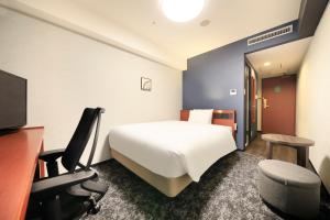 a hotel room with a bed and a desk and a tv at Richmond Hotel Yokohama-Bashamichi in Yokohama