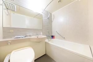 a white bathroom with a toilet and a sink at Richmond Hotel Yokohama-Bashamichi in Yokohama