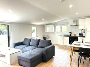 a living room with a blue couch and a kitchen at La Farfallina, maison de plain-pied avec garage in Limoges