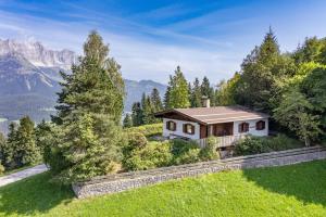 une maison sur une colline avec des montagnes en arrière-plan dans l'établissement Ferienhaus Soregina, à Ellmau