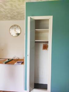a door to a closet with a clock on a wall at studio du parc piscine in Souillac +7 photos