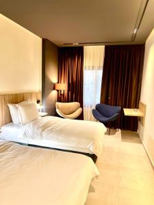 塔扎Hôtel Le Manoir的一间带床和椅子的酒店房间
