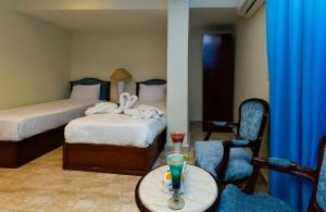 a hotel room with two beds and a table and chairs at Glory Pyramids Inn in Cairo