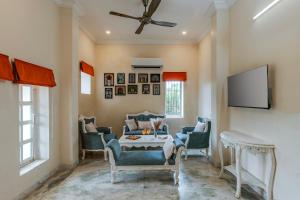 a living room with a couch and chairs and a tv at ELIVAAS 3 BHK with Pvt Pool & Lush Garden - Oakwood Villa in Jaipur