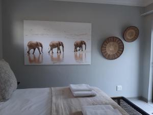 a painting of three elephants walking in a bedroom at The Bird Hide Luxury Self catering Chalets in White River