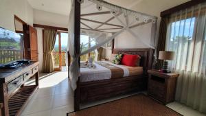a bedroom with a canopy bed and a television at Villa Santai Karangasem in Tirtagangga