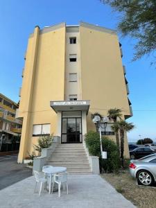 een gebouw met een tafel en stoelen ervoor bij Apartament Mare e Sole z basenem i przy plaży in Marotta