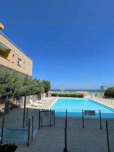 een groot zwembad met stoelen en een gebouw bij Apartament Mare e Sole z basenem i przy plaży in Marotta