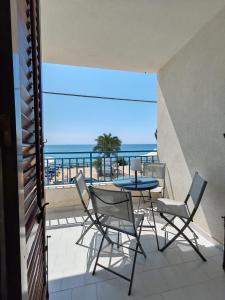 Un balcón con mesa y sillas y el mar. en Casa Azzurra - Terrazza sul mare, en Marinella di Selinunte