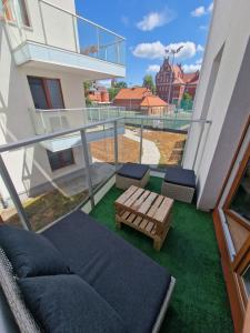 a balcony with a couch and a bench on the grass at Apartament w Centrum z wanną z hydromasażem in Kętrzyn