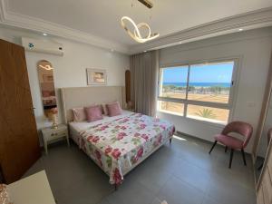 a bedroom with a bed and a large window at Panorama Apartment Zone Touristique Haut Standing in Mahdia