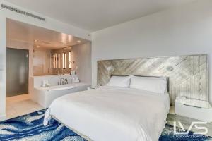 a bedroom with a large white bed and a bathroom at W Hotel Ftl Beach 1509 Oceanview 2Bed 2Bath Condo Resort in Fort Lauderdale