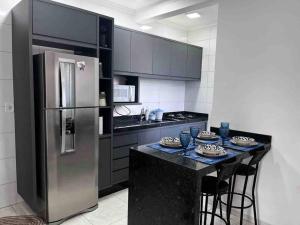 a kitchen with a stainless steel refrigerator and a table at Apartamento Doce Lar in Dourados