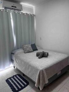 a bed in a white room with a window at Apartamento Doce Lar in Dourados