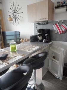 a kitchen with a counter with two bar stools in it at Appartement PuySaintVincent 1600 in Puy-Saint-Vincent +4 photos