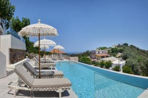 a swimming pool with chaise lounge chairs and an umbrella at Alexandras's Mansion - Alexinia's House in Ayiá