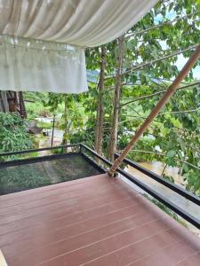 a wooden walkway with a canopy on a porch at บ้านชมจันทร์ บ้านสวนสราญชล in Ban Nong Bo