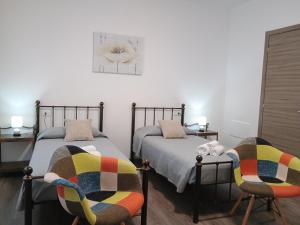 two beds in a room with two chairs at Harmony Affittacamere in Tortolì