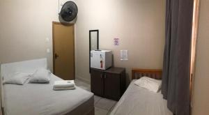 a room with two beds and a clock on the wall at Hotel Laçador in Santa Maria