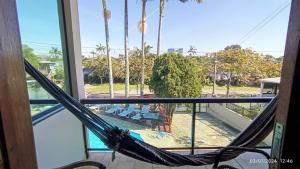 a hammock in a room with a view of a pool at Pousada Baía dos Corais in Penha