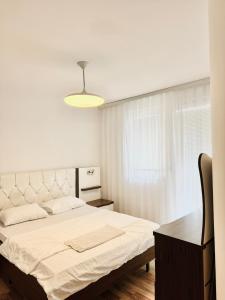 een witte slaapkamer met een groot bed en een bureau bij Park Street Apartments in Pristina