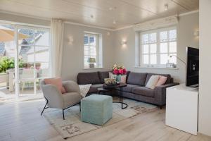 ein Wohnzimmer mit Sofa, Sesseln und Fernseher in der Unterkunft Bäum Hüs A in Westerland