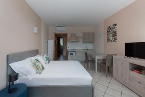 sypialnia z białym łóżkiem i kuchnią w obiekcie Il Sogno Apartments w mieście Desenzano del Garda