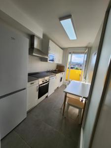a kitchen with white cabinets and a table and a window at Apartamento Santander Maliaño in Maliaño
