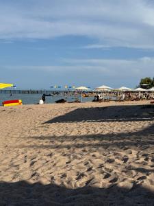 a sandy beach with umbrellas and the ocean at Алые Паруса in Cholpon-Ata