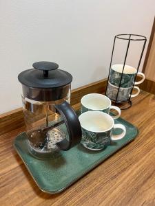 Una cafetera y dos tazas sobre una mesa en Life Luxury Lodgings near IT PARK, en Cebú